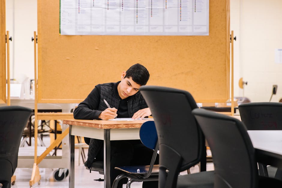 Young man focused on writing in a classroom, ideal for education concepts